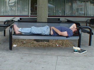 Some dude napping in a park with his hands in his pants