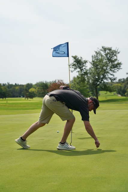 Fixin the ball mark. He damn near backed that thing up right into the hole.