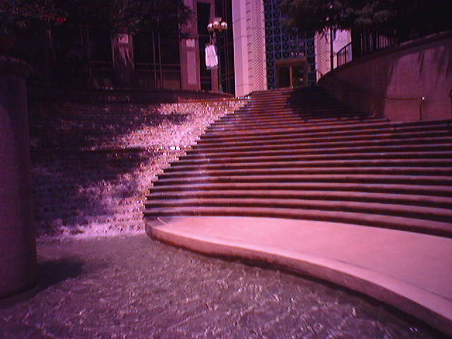 A waterfall next to stairs along the riverwalk