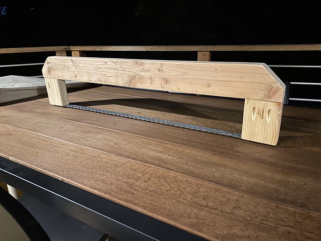 A scrap wood attempt at preventing rain/snow from pooling up the patio table cover