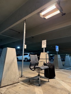 This chained up office chair under a heating lamp at DTW feels very Detroit