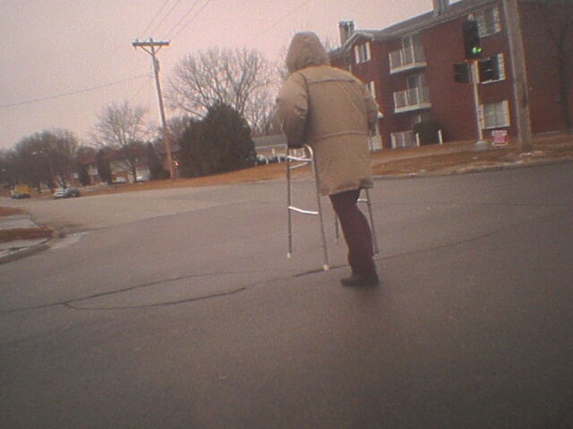 An old man bookin' across an intersection