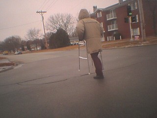 An old man bookin' across an intersection