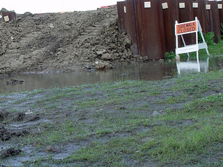 Sidewalk closed by metal, dirt, and water