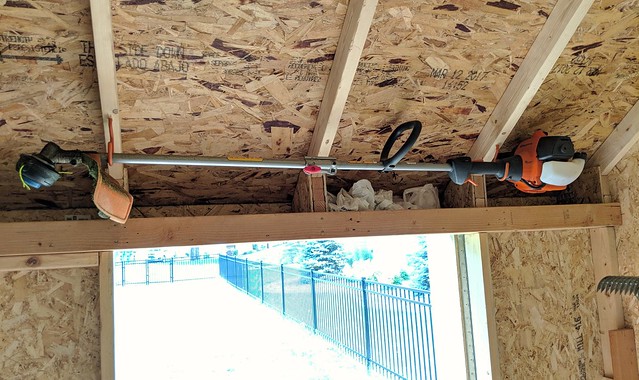 Snuck the weed eater in above the door with some old bike hooks
