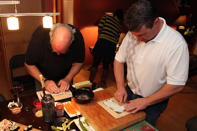 Dudes rolling sushi