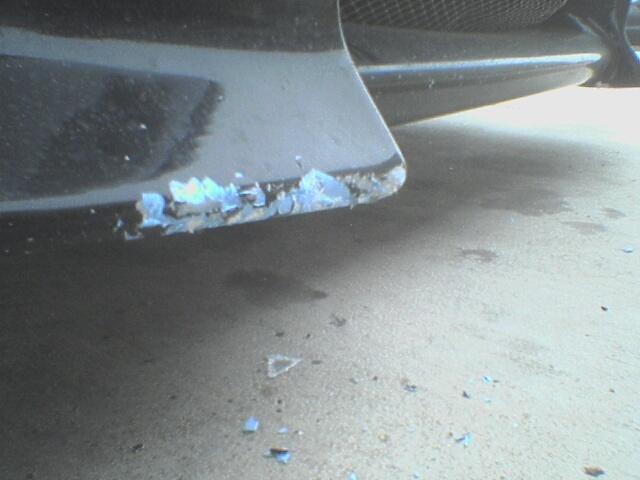 Mechanic hit a curb with my car - notice the fiberglass chips on the ground