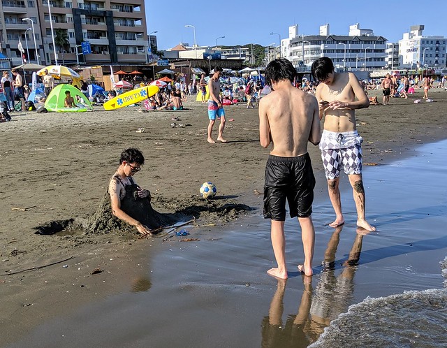 Weird boy is having fun in the black sand