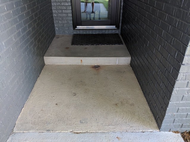 Different generations of concrete, textures, and rusts on the entryway sidewalk